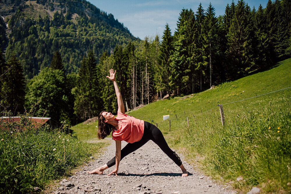Yoga teacher doing yoga pose without a mat in nature at the french Alps