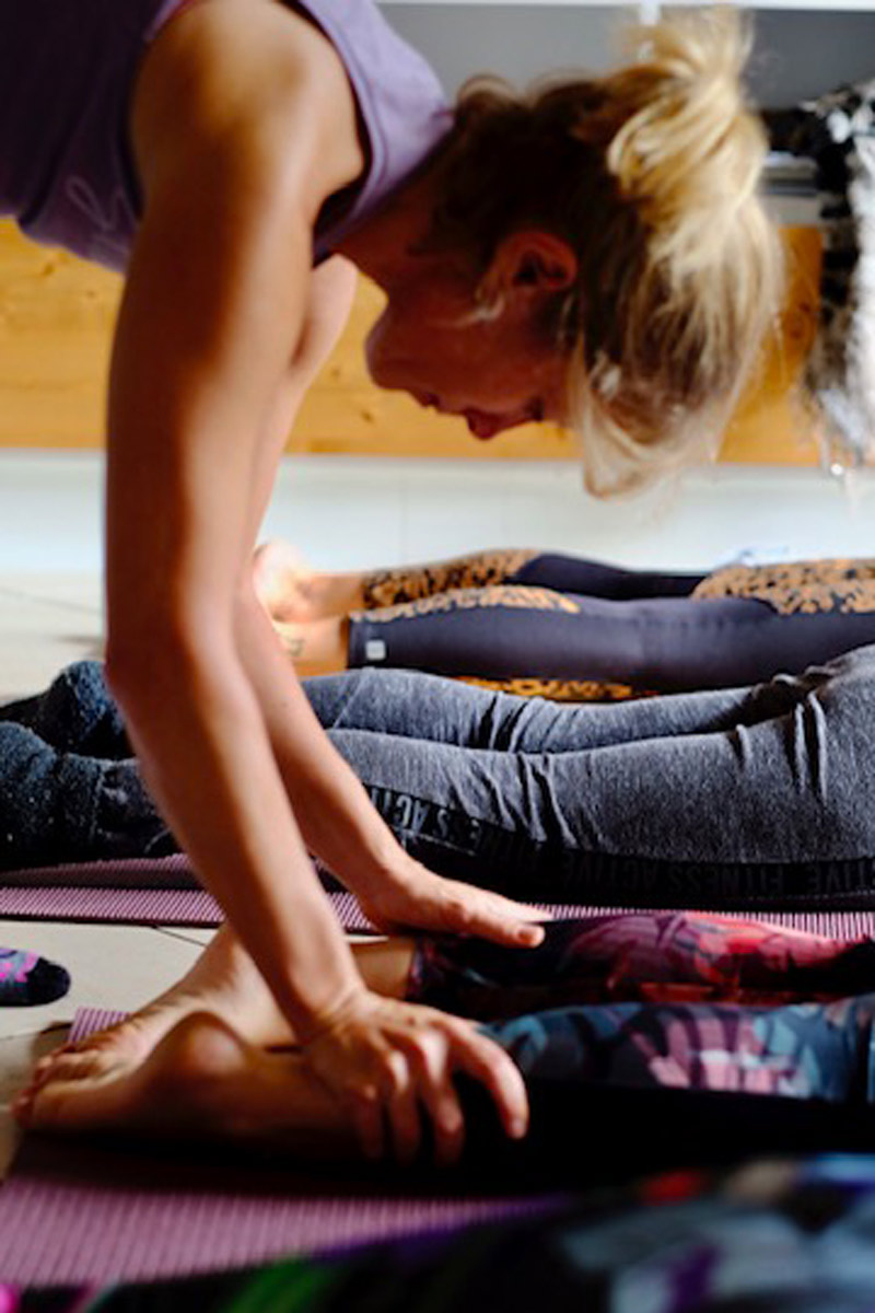 Yoga teacher Carine Torres helping student