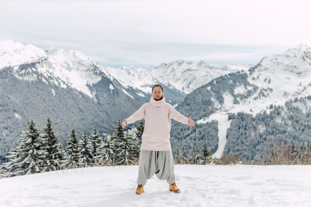 A qi gong teacher leading an online class at the top of a snowy mountain in the alps